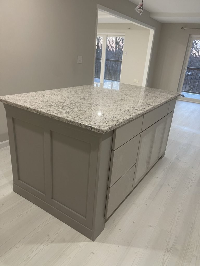 Kitchen island with raised-panel wainscot and granite top