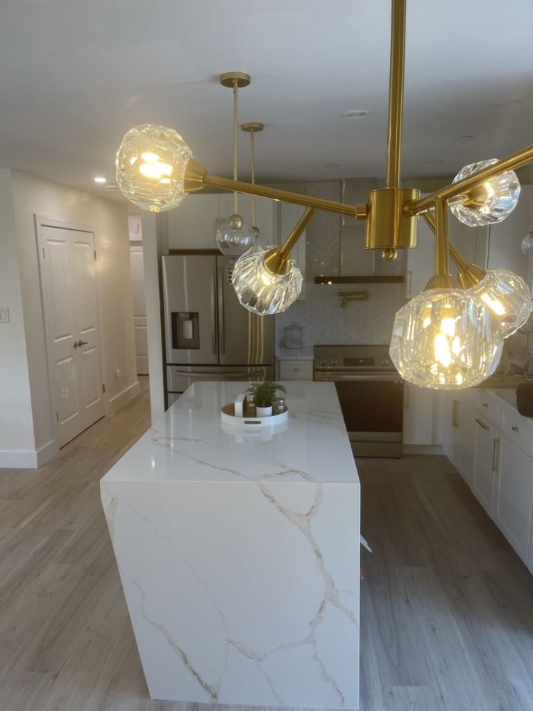 Kitchen remodel with brass globe chandelier over a white quartz waterfall island
