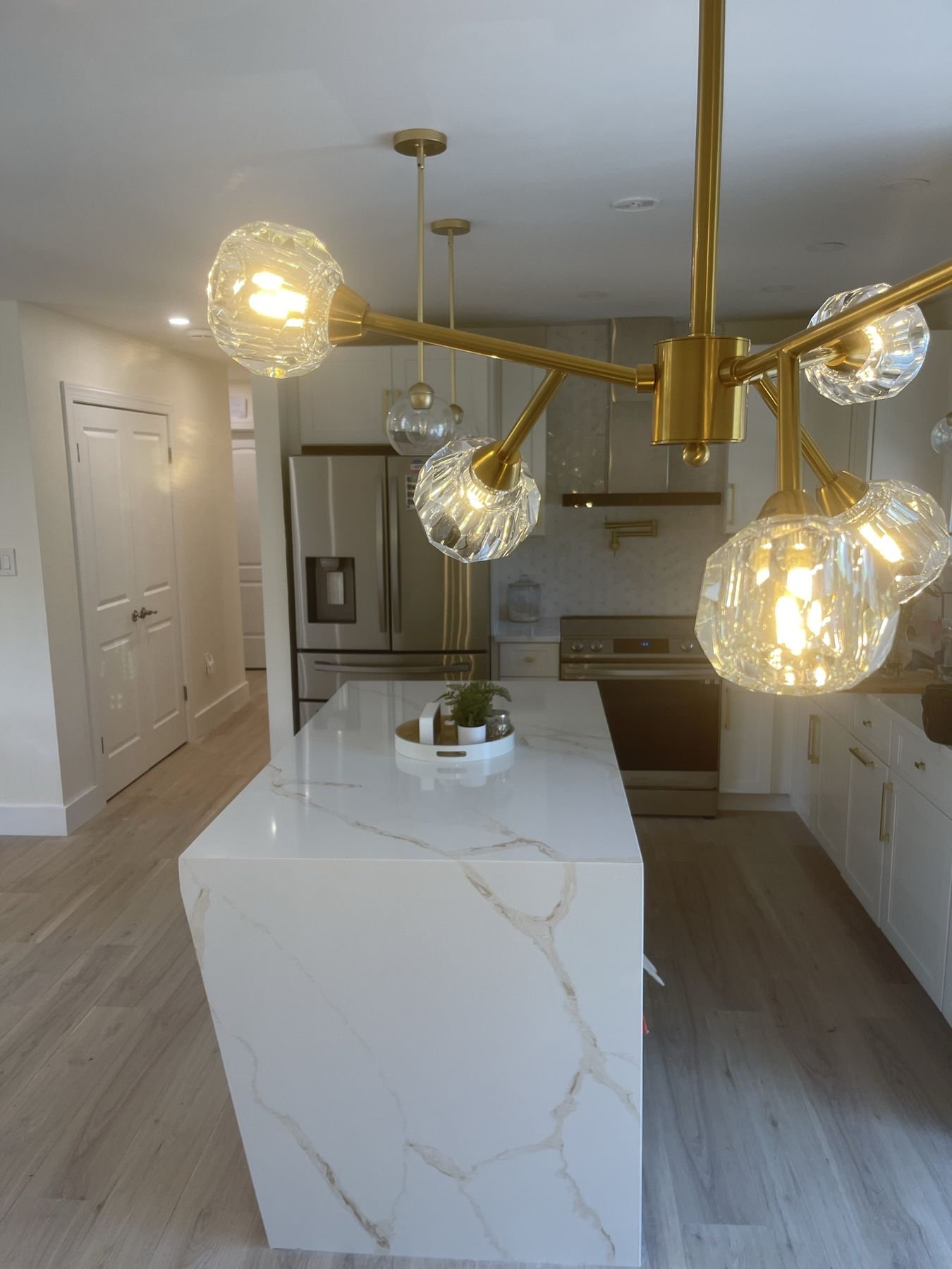 Kitchen remodel with brass globe chandelier over a white quartz waterfall island