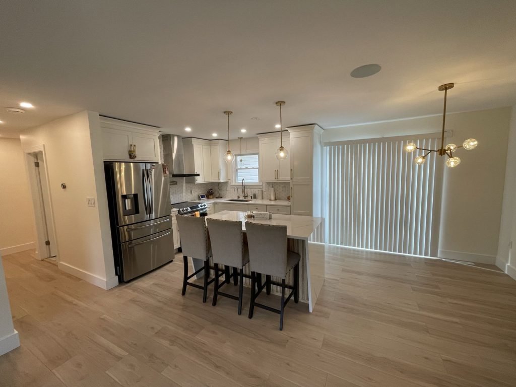 Renovated open kitchen and dining room with brass lighting and wood-look floors