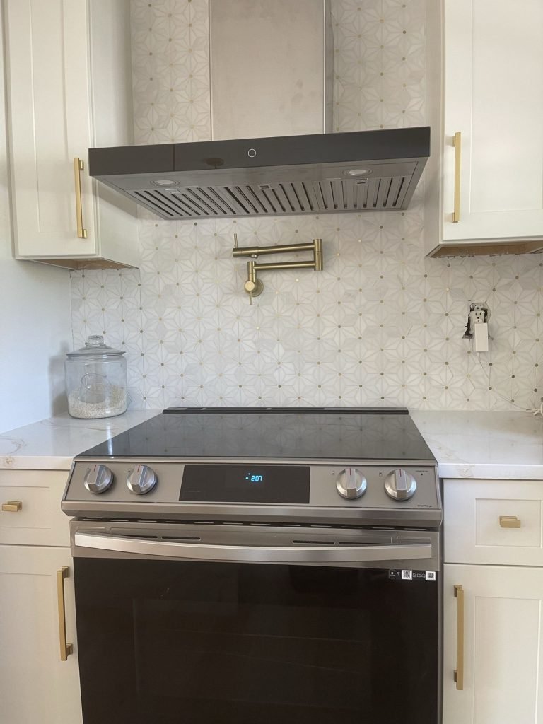 Stainless range hood and brass hardware in a white shaker kitchen