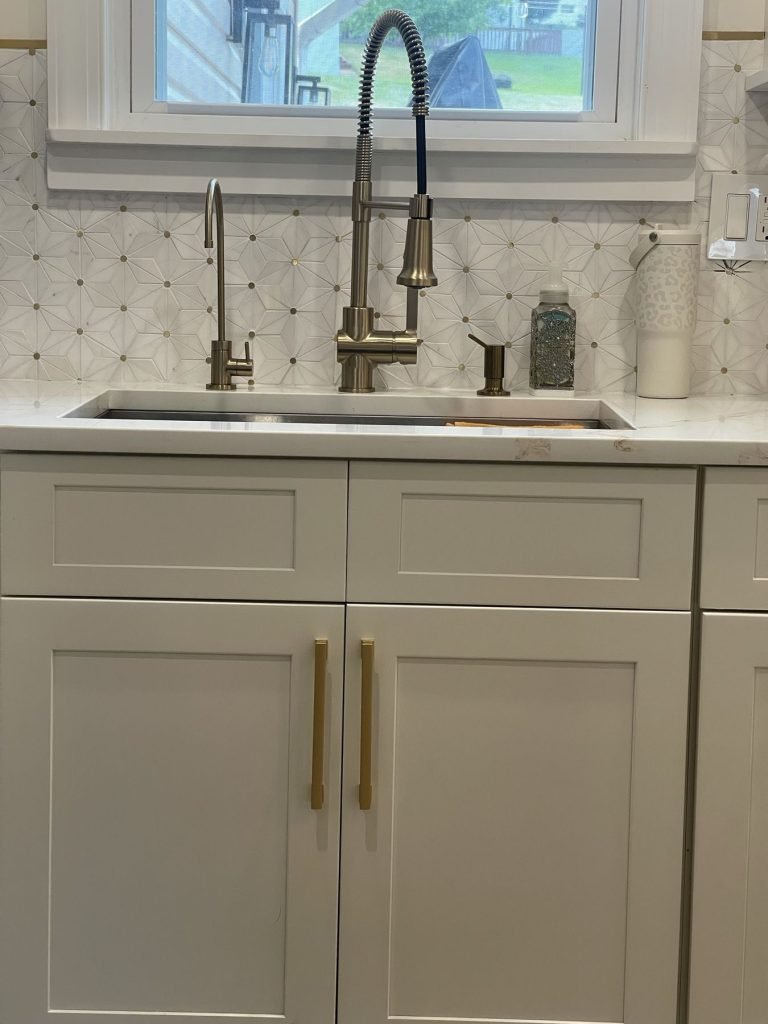 Brass bridge faucet and mosaic backsplash over a kitchen sink