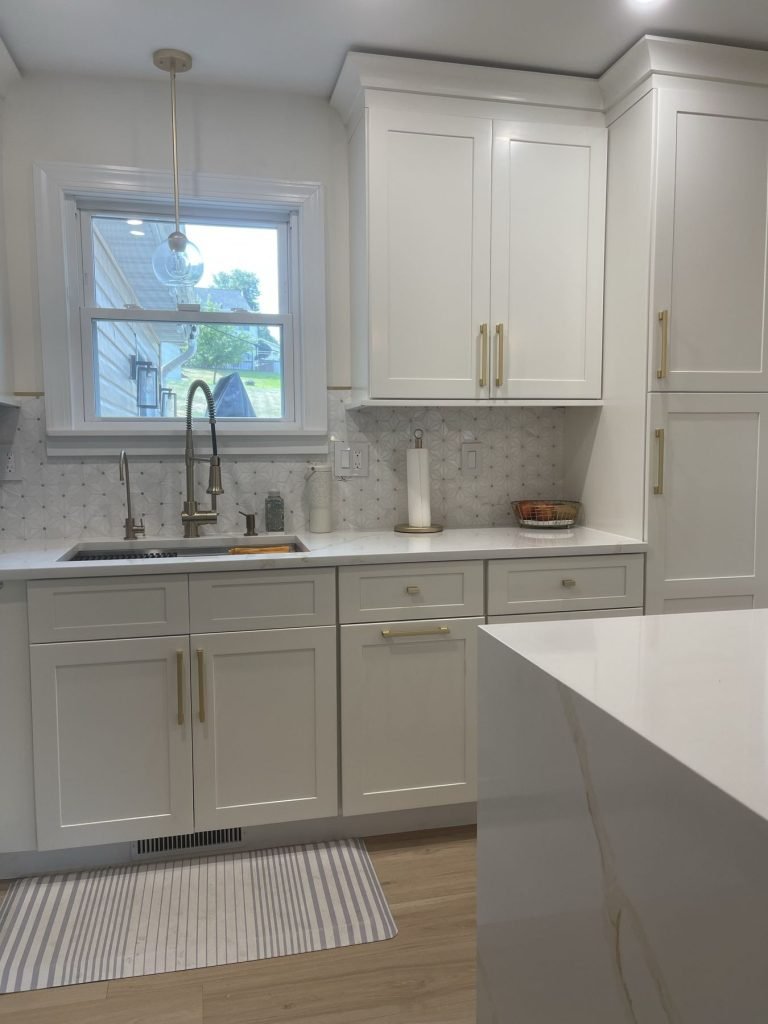 White kitchen sink wall with brass faucet and shaker cabinets
