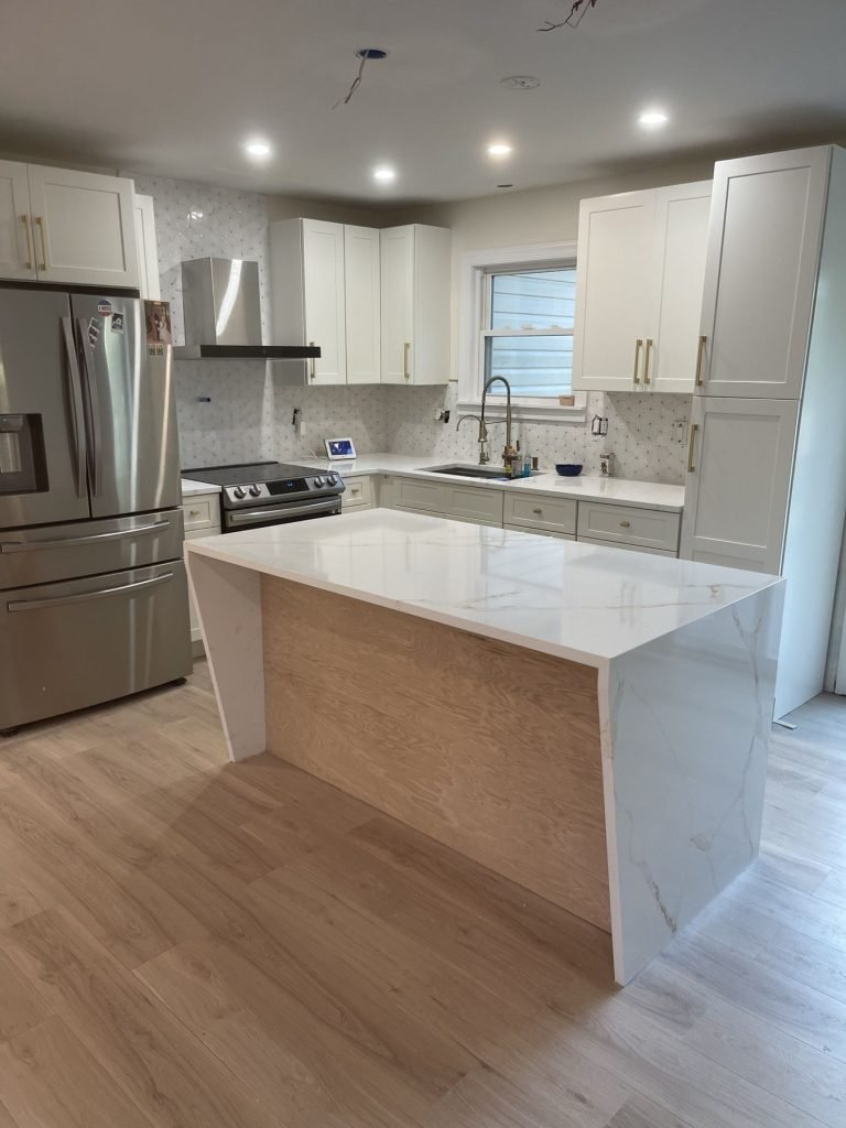 Custom kitchen with marble-look quartz waterfall island and white shaker cabinets