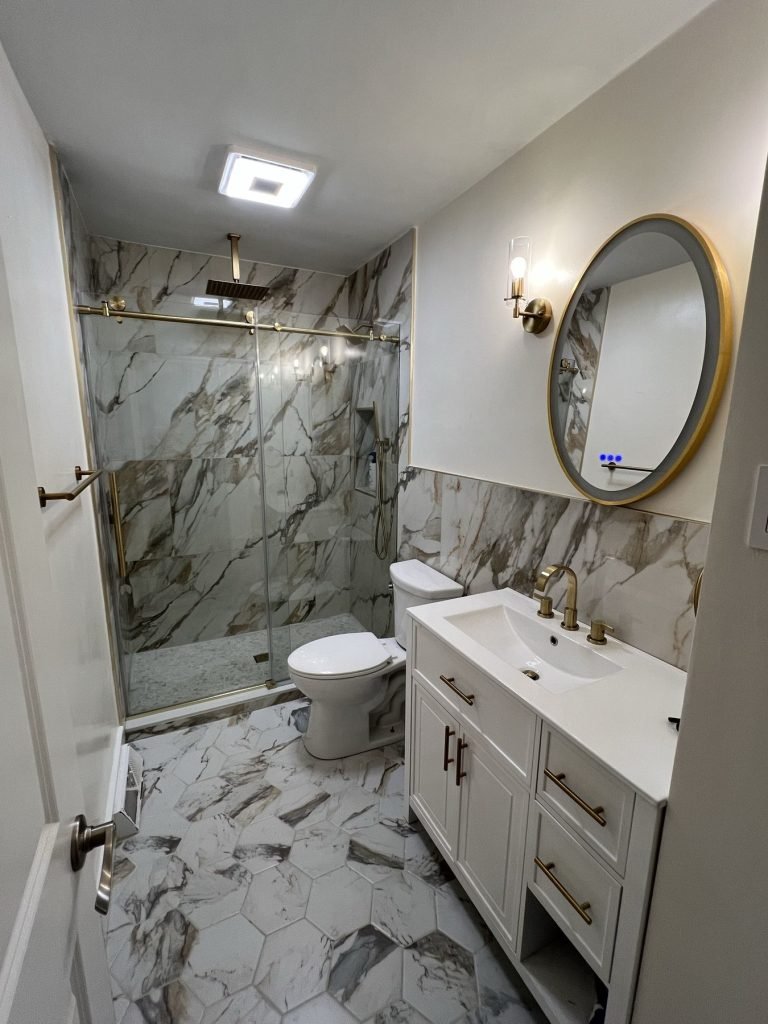 Bathroom remodel with marble-look shower and round mirror