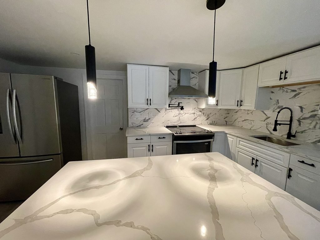 Marble-look quartz island under black pendant lights
