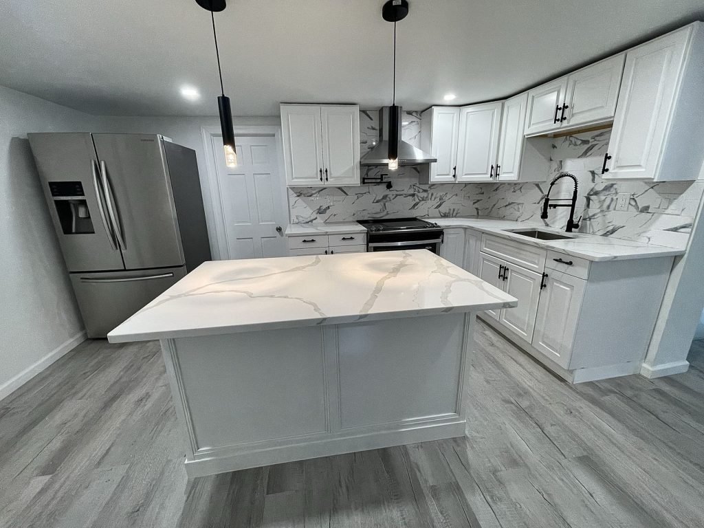 Farmhouse kitchen remodel with marble-look island and black pendants