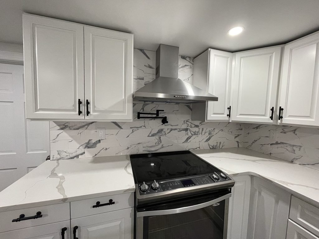 White shaker kitchen with marble-look backsplash and chimney hood