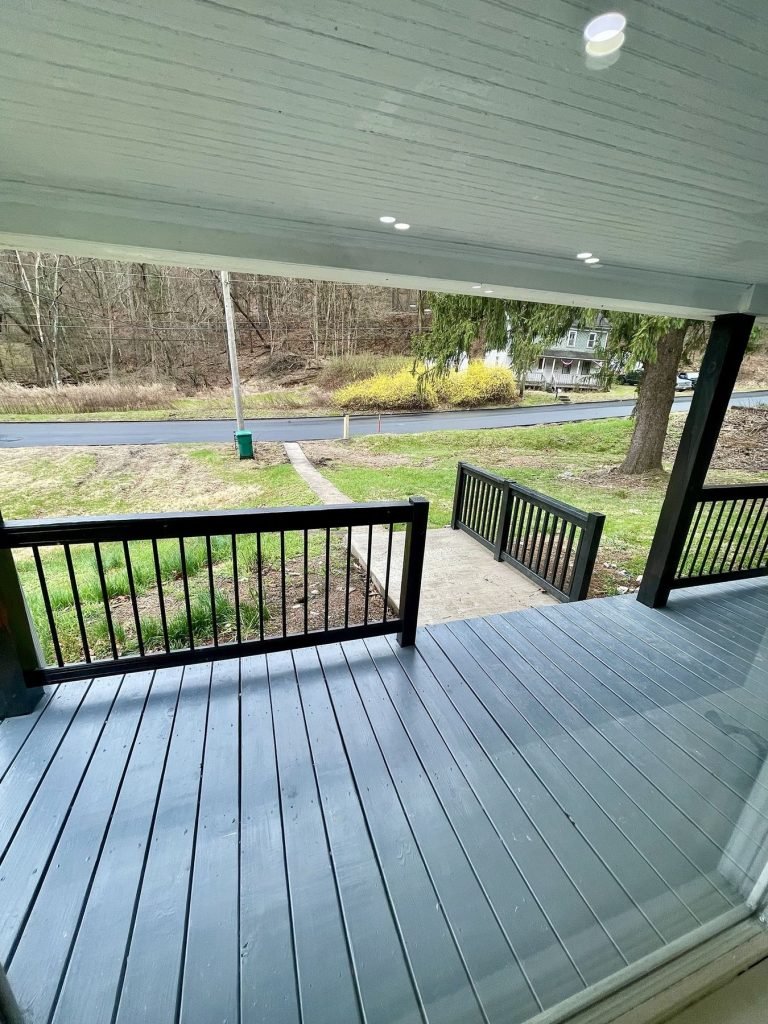 Covered porch deck with gray boards and black railing