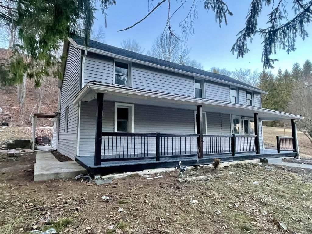 Farmhouse exterior with new wraparound porch and black railings