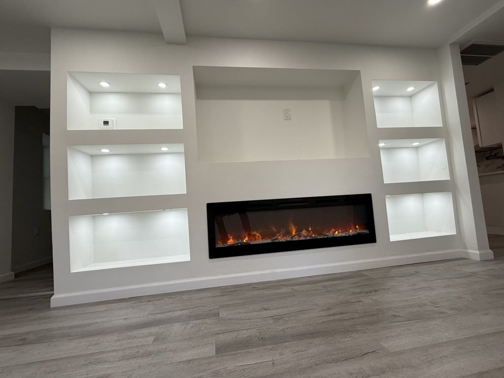 Custom built-in wall with lit shelving and linear electric fireplace