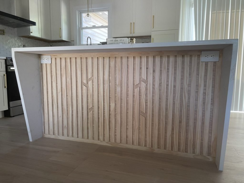 Fluted wood panel island front between quartz waterfall ends