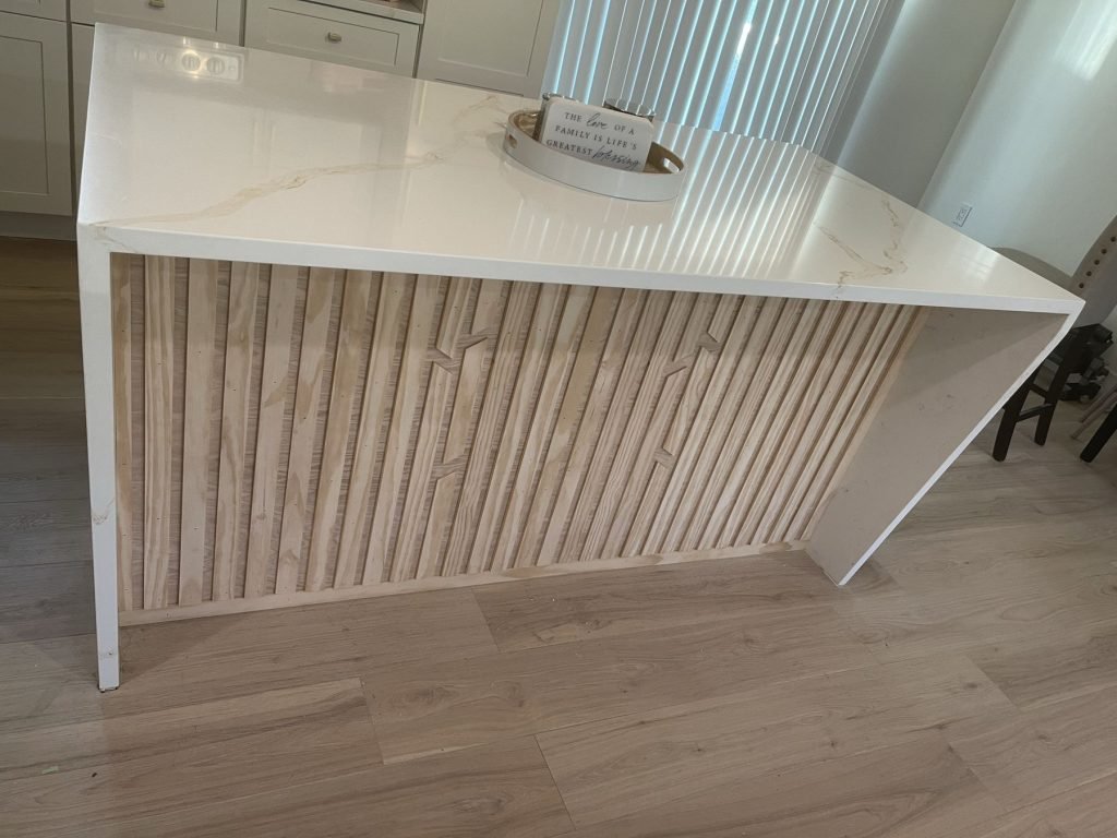 Waterfall quartz island with fluted wood panel detail