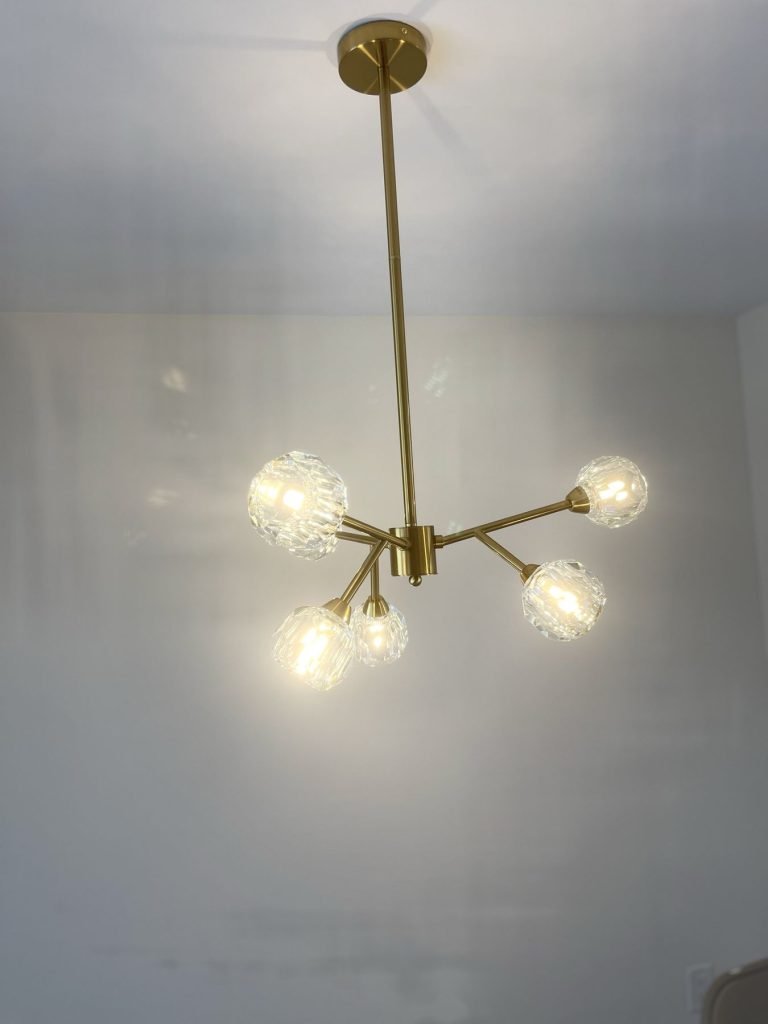 Brass globe chandelier installed in a renovated dining area