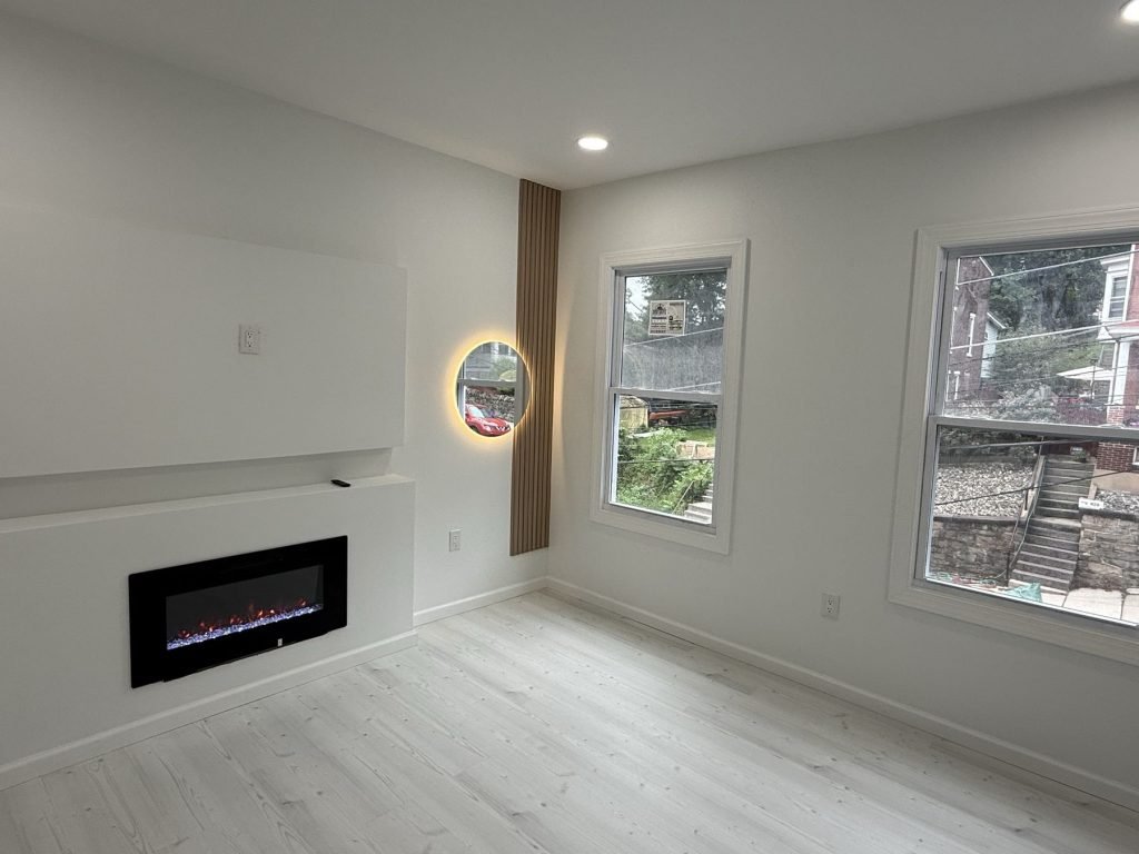 Living room with linear fireplace and round LED mirror accent