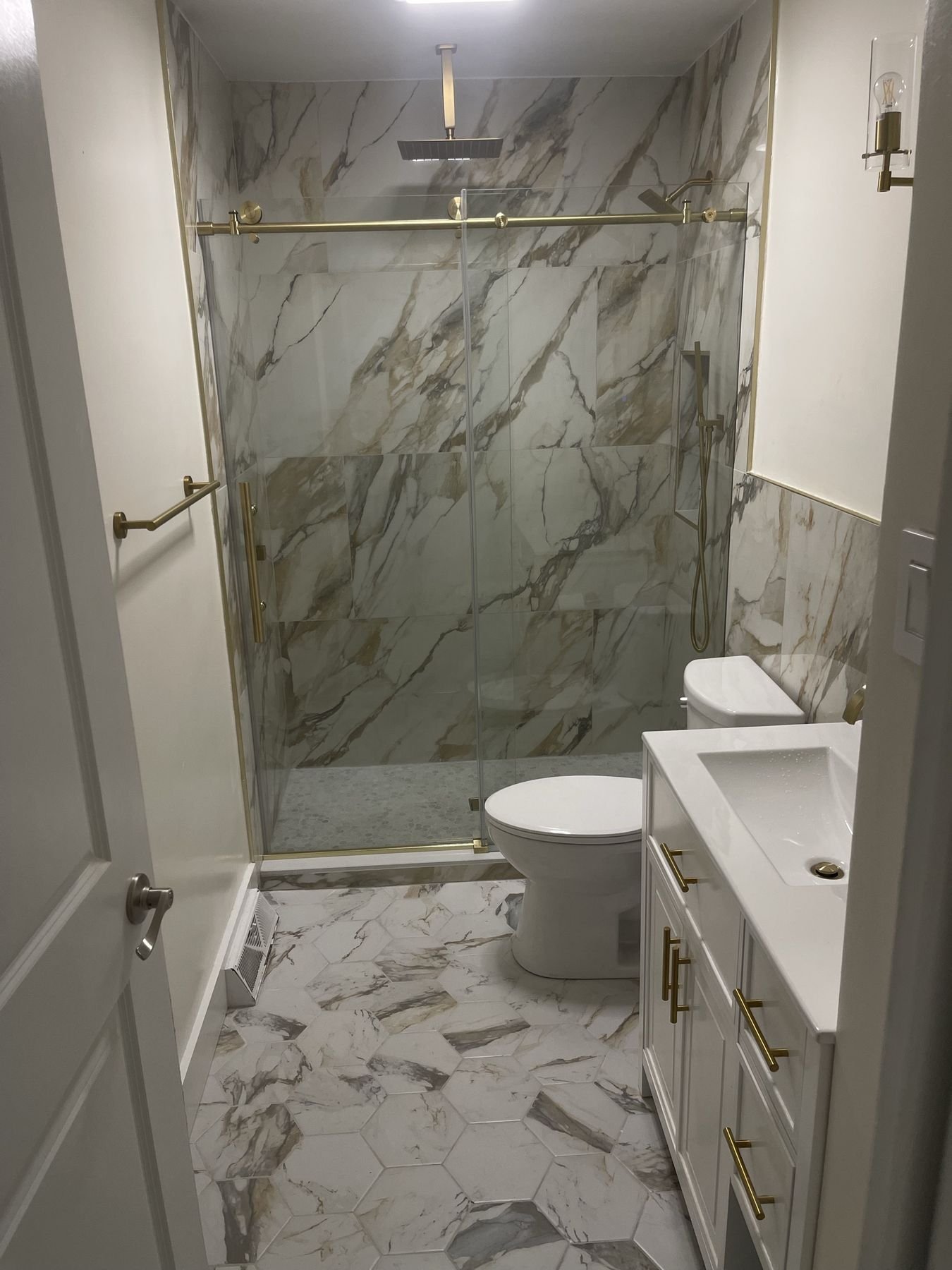 Bathroom remodel with marble-look porcelain shower and brass frameless glass door