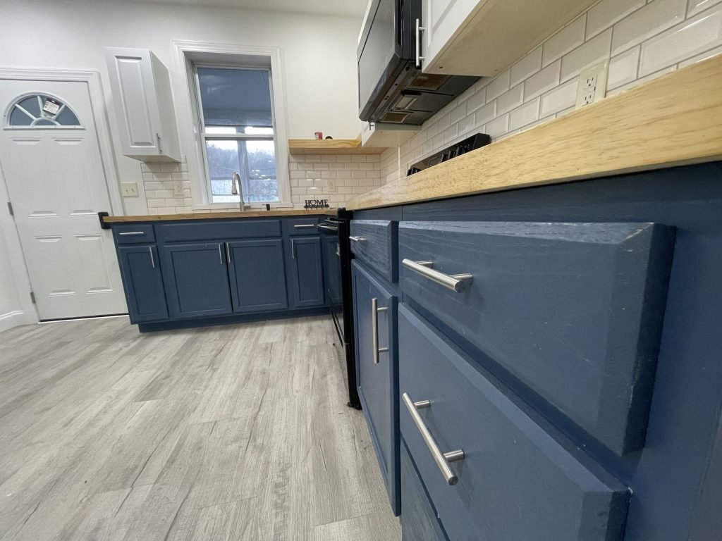 Navy shaker cabinets with brushed hardware and wood counters