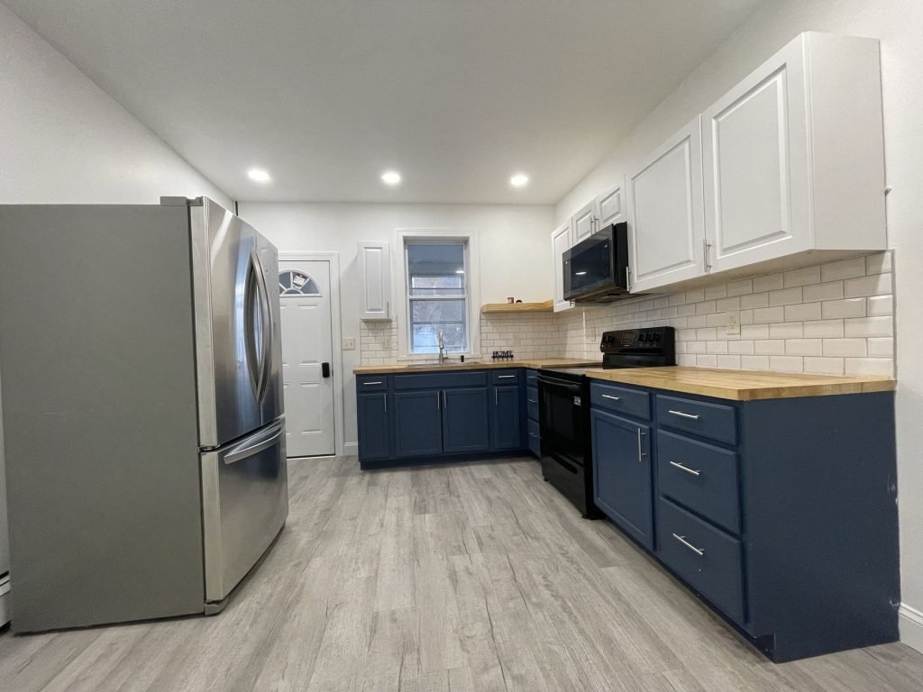 Kitchen remodel with navy lower cabinets and butcher block counters