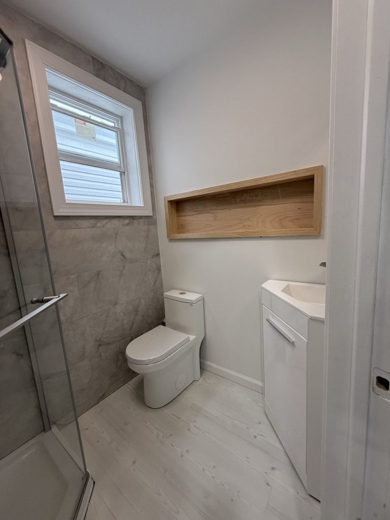 Bathroom with wood-lined shower niche and glass partition