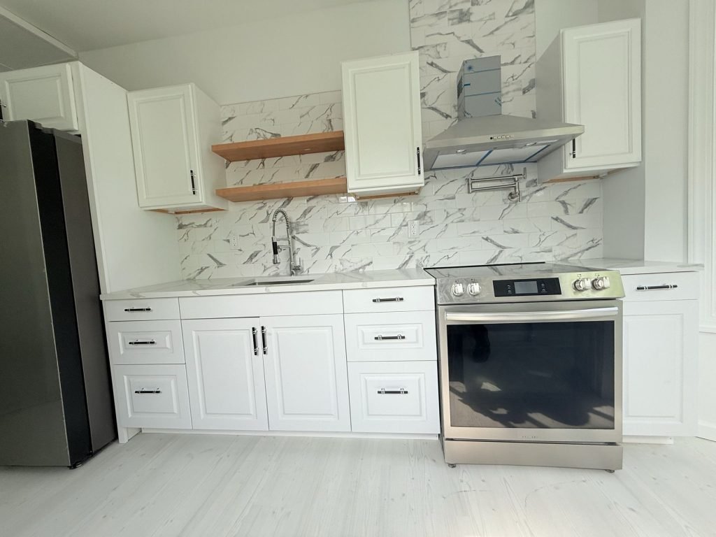 White kitchen with marble backsplash and wood floating shelves