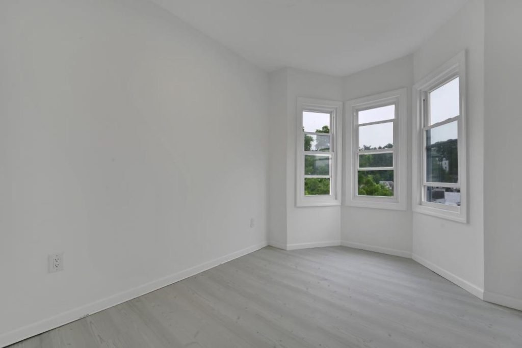 Renovated rowhouse room with bay windows and new flooring