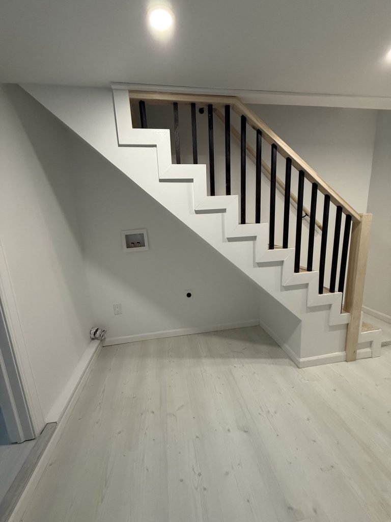 Staircase with black iron balusters and wood handrail