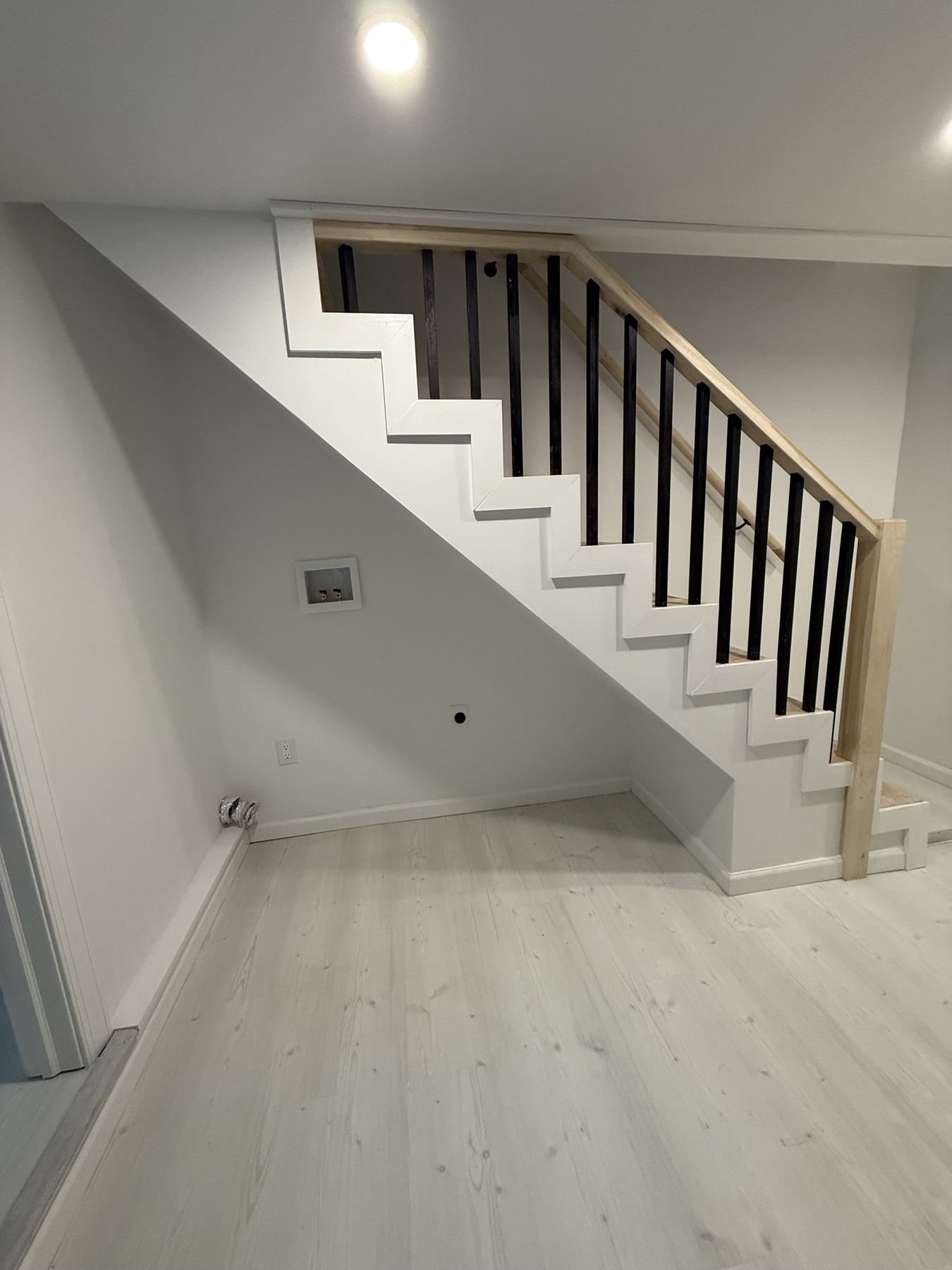 Staircase with black iron balusters and wood handrail